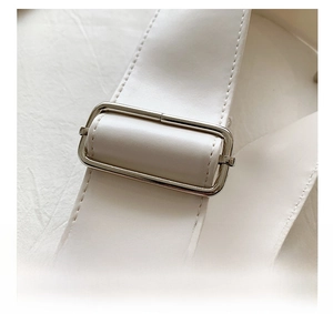 Detail of adjustable white leather strap with silver metal buckle on a large tote bag