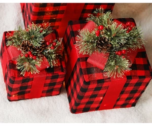 Detail of red and black buffalo plaid Christmas gift boxes with pine cones and berries