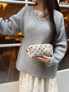 Sherpa heart-print cosmetic bag held by model, showcasing fuzzy texture and compact size
