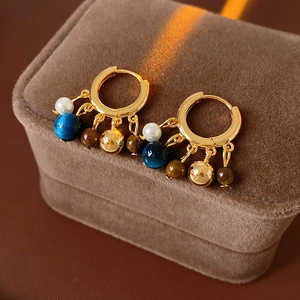 Macro view of vintage gold hoop earrings with multi-color beads on brown velvet