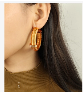 Detail shot of a model wearing a gold twisted hoop earring with sparkling rhinestones