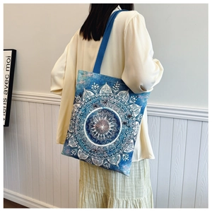 Back view of a woman wearing the blue mandala print canvas tote bag with shoulder straps