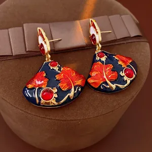 Vintage gold fan earrings with dark blue enamel and red leaf patterns on velvet