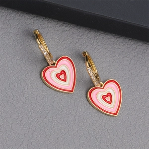 Macro shot of gold heart earrings with red pink and white enamel and inlaid small crystals
