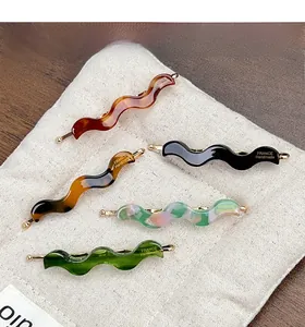 Detail of five wavy acetate hair clips with gold FRANCE Handmade text on a canvas base