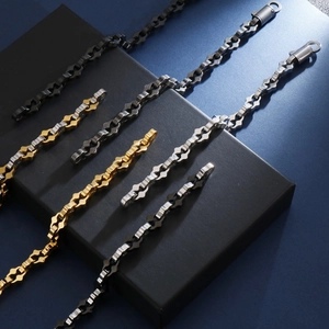 Détail de chaînes à maillons gourmette en or, noir et argent sur un coffret cadeau