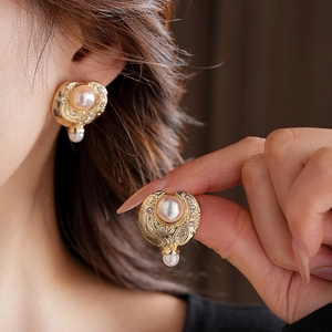 Détails de boucles d'oreilles vintage en perles dorées portées par un mannequin chic