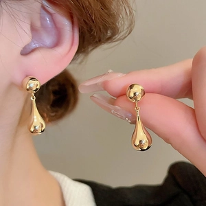Close-up of golden leaf-shaped drop earrings worn by a model for a luxury look