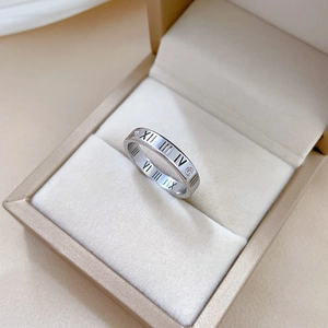 Macro detail of silver titanium ring featuring Roman numerals and small embedded crystal