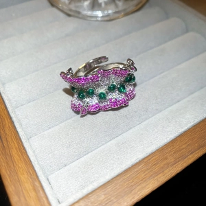 Détails d'une bague vague en argent sertie de cristaux et de pierres vertes sur velours