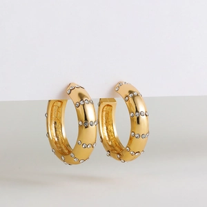 Détail des boucles d'oreilles créoles dorées en C ornées de strass brillants incrustés