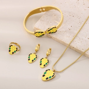 Detailed set of gold jewelry with colorful hexagonal enamel patterns on stone background