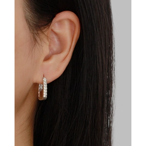 Macro shot of silver handbag-style earrings with a twisted metal texture and minimal design