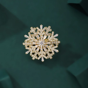 Close-up of a rotating golden snowflake brooch with zircon crystals on a green pedestal