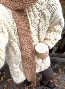 Detail of chunky cable knit sweater and matching scarf set in cream and coffee tones