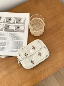Quilted white storage bag with cherry pattern on a wooden table with lifestyle props