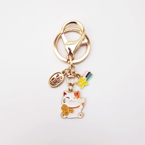 Close-up of Maneki Neko keychain with lucky gold coin and rainbow star pendant