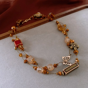 Detail of vintage flower ceramic beads and alloy butterfly pendants on double-layer necklace