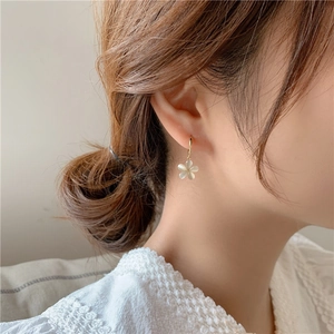 Elegant gold flower earrings with white cat-eye petals on a model for a stylish look