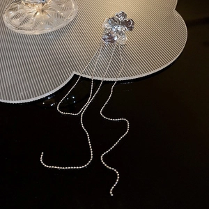 Détail d'un ear cuff floral argenté avec de délicats longs glands en chaîne de perles