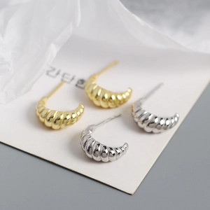 Detail of gold and silver horn-shaped earrings with spiral texture on s925 silver studs