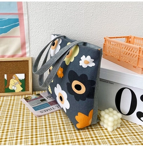 Detail of grey canvas tote bag featuring vibrant floral prints in a lifestyle setting