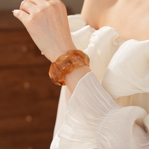 Detail of vintage amber acrylic wide elastic bracelet with marble texture on model wrist