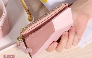 Gros plan d'un petit portefeuille rose avec pompon, fentes pour cartes et zip