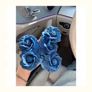 Close-up of five denim blue rose hair clips with detailed frayed edges held in hand