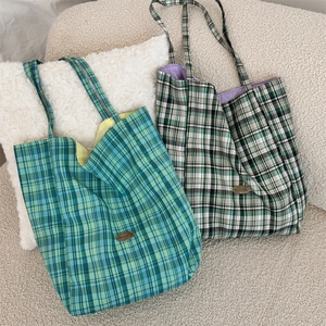 Detail of checkered canvas tote bag with contrast lining and metal logo on a cozy sofa