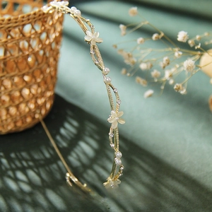 Macro view of gold leaf headband with white cat eye stone flowers and pearls