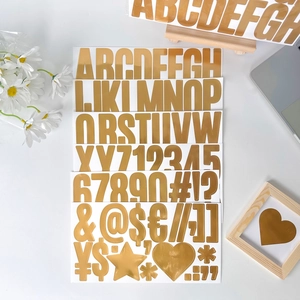 Close-up of 2.5 inch gold alphabet and number stickers on a minimalist desktop setup