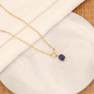 Dettaglio ravvicinato di una collana con ciondolo in pietra naturale su piatto bianco