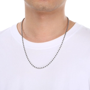 Détail d'un collier chaîne à billes en acier inoxydable argenté porté sur un t-shirt blanc