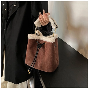 Detail of suede bucket bag with white faux shearling trim and drawstring closure