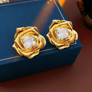Détail macro de boucles d'oreilles fleur or 18k avec cristal carré dans un écrin à bijoux