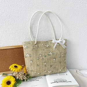 Handwoven straw tote bag with white floral embroidery and delicate lace bow decoration