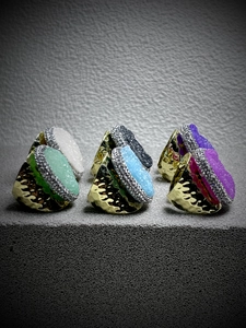 Close-up of three bronze adjustable rings with colorful raw crystals and rhinestone details