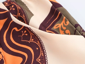 Macro shot of silky fabric with vintage patterns in orange and deep purple tones