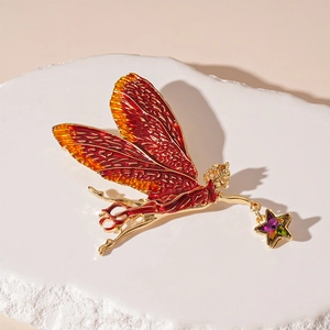 Macro detail of fairy brooch with red enamel wings and colorful star crystal