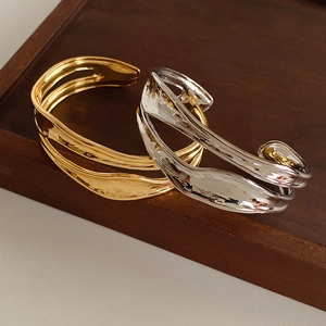 Detail showing wavy irregular gold and silver bangles with fluid liquid metal texture