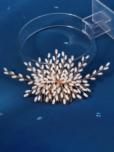 Detailed close-up of golden bridal hair comb with elegant white pearls and floral wire design