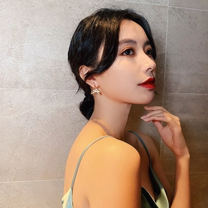 Detail of elegant gold fish tail drop earrings with sparkling rhinestones on model