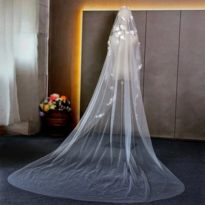 Detail of white bridal veil with 3D handmade flowers and pearls on long tulle