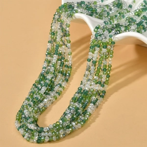 Macro detail of 3mm green and clear faceted wheel beads on a wave ceramic plate