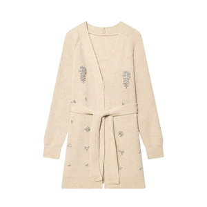Détail d'un cardigan en maille beige orné de motifs d'étoiles en strass argentés