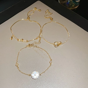 Detailed macro of three gold-plated adjustable bracelets with zircon and shell pearls