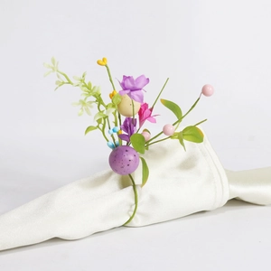 Detail of Easter napkin ring with purple eggs, faux flowers and green foliage decoration