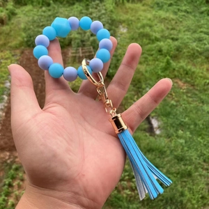 Dettaglio del portachiavi a perle in silicone blu e viola con gancio dorato e nappa