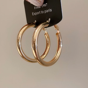 Detailed close-up of large polished golden hoop earrings with a sleek metallic finish